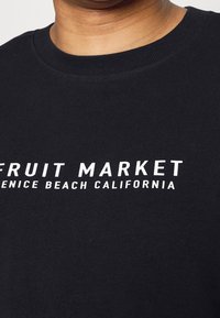 T-shirt in cotone nero con il testo bianco audace "FRUIT MARKET VENICE BEACH CALIFORNIA." Design a girocollo con una texture morbida.