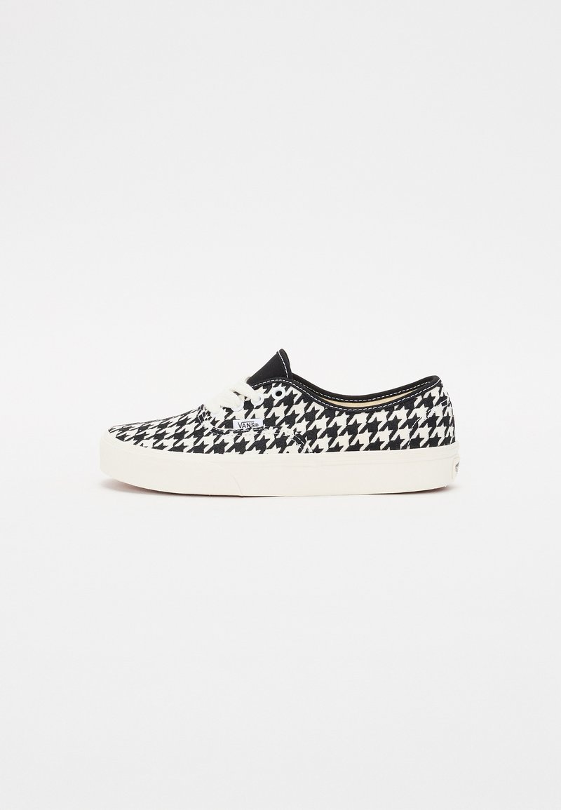 Black and white houndstooth pattern sneaker with a textured canvas upper, round toe, white lace-up closure, and rubber sole.