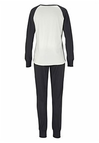 Black and white long-sleeve top with raglan sleeves, paired with matching black pants. Comfortable fabric with elastic cuffs and waistband.