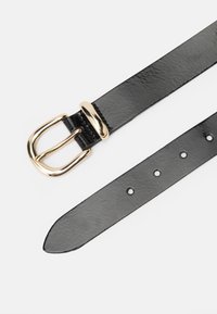 Curea din piele neagră cu o cataramă din metal aurit, având gauri uniform distanțate și o textură netedă, îngustându-se spre capătul ascuțit.