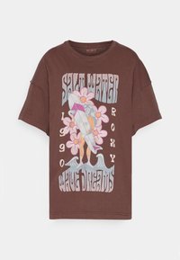 Camiseta de gran tamaño marrón con un gráfico retro de surf que incluye flores, una tabla de surf y texto. Hecha de algodón suave y con mangas cortas.