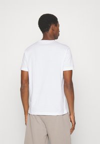 T-shirt bianco a maniche corte con colletto rotondo, realizzato in cotone. Presenta un design semplice senza motivi o accenti visibili.