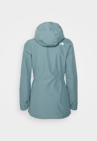 Světle modrá voděodolná bunda s kapucí, elastickým pasem, dlouhými rukávy a logem The North Face na horní části zad.