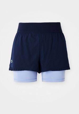 Marineblå plisserte tennis skjørt med lyseblå, tettsittende shorts under og en bred ribbet midjebånd.
