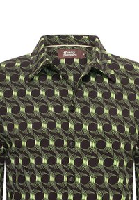 Camisa de manga corta de tela negra con un patrón geométrico en verde lima de olas y círculos. Tiene un cuello y botones en la parte frontal.