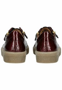 Zapatos de charol burdeos con acabado texturizado, acentos de hardware dorado y suela de goma beige con estrías horizontales.