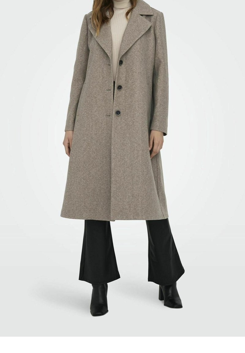 Abrigo largo gris de mezcla de lana, con cuello en pico, botones dobles y silueta recta, combinado con pantalones negros acampanados.