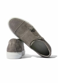 Sive čizme od suède s duplim srebrnim kopčama, zaobljenim vrhom i bijelim gumastim potplatom; teksturirana površina i minimalistički dizajn.