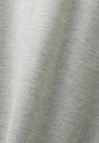 Ljusgrått tyg med en mjuk textur, med ett subtilt melerat mönster. Materialet hänger snyggt med mjuka veck.