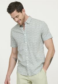 Chemise à manches courtes à boutons de couleur vert clair avec un motif géométrique. Le tissu a une texture lisse avec un éclat subtil. Boutons blancs visibles.