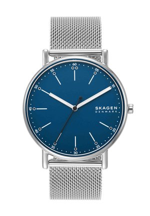 Reloj con correa de malla plateada, esfera azul, agujas blancas de horas y minutos, aguja negra de segundos y logotipo de Skagen Denmark a las 3 en punto.