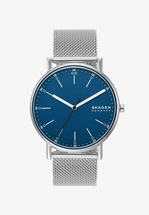 Silberne Mesh-Uhr mit blauem Zifferblatt, weißen Stunden- und Minutenzeigern, schwarzem Sekundenzeiger und Skagen Denmark Logo bei 3 Uhr.