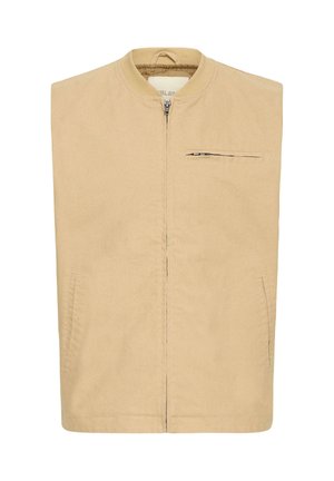 Beige ermeløs jakke med glidelås foran, høy krage, to sidelommer og en liten glidelåslomme på brystet.