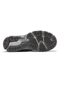 Μαύρη και γκρι σόλα αθλητικού παπουτσιού με περίπλοκο σχέδιο πέλματος, που διαθέτει εξαγωνικές λαβές και μια λεία περιοχή για ευκαμψία.