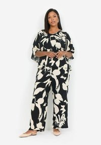 Haut à motif floral en noir et blanc et pantalon à larges jambes en tissu léger, avec une coupe décontractée et un design fluide.