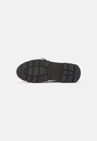 Semelle de chaussure en caoutchouc noir avec des grips texturés, présentant un embout arrondi et un design à rainure centrale pour la traction. Marquée "Fabriqué au Portugal."