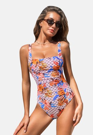 Maillot de bain avec un motif floral en orange, bleu et rose sur un fond clair, avec un encolure carrée et des bretelles larges.