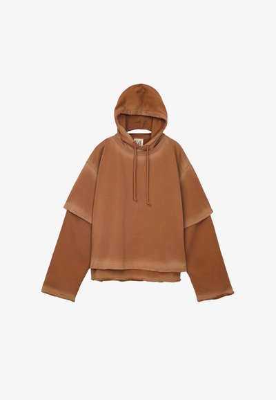 Hoodie brown oversized con maniche sovrapposte, cappuccio con cordini e dettagli con orlo grezzo su sfondo bianco.