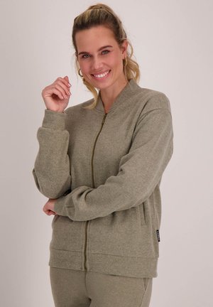 Groene bomberjack met textuur, ritsluiting, geribbelde manchetten en tailleband. Heeft steekzakken aan de zijkant en subtiele branding op de zoom.