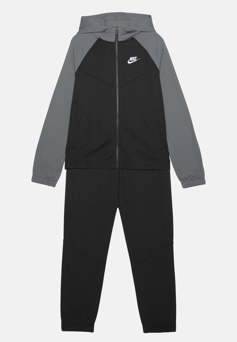 Tuta Nike con giacca grigia con cappuccio e accenti neri, chiusura con zip e tasche laterali. I pantaloni sono neri con un design tapered.