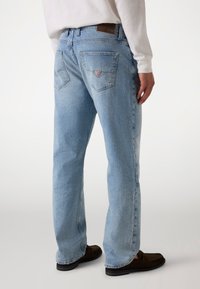 Los jeans de mezclilla de color azul claro presentan un diseño de pierna recta con dos bolsillos traseros, una etiqueta de cuero en la cintura y sutiles acentos descoloridos.
