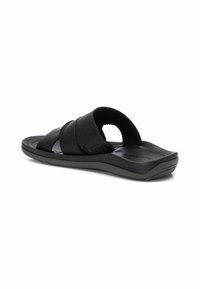 Chanclas negras con tiras de cuero cruzadas, plantilla texturizada y una suela de goma acolchada para mayor comodidad y soporte.