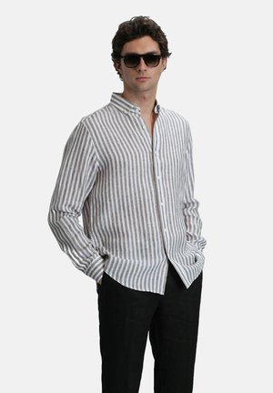 Striped, button-up shirt in light beige and gray fabric. Features a collar, long sleeves, and relaxed fit. Worn with black trousers.