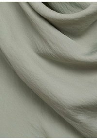 Light grey fabric features a soft, textured surface with subtle diagonal patterns, draped elegantly with gentle folds.