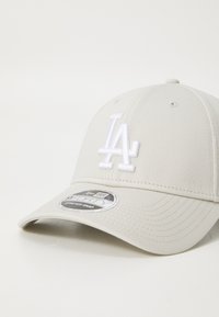 Világosszürke baseballsapka texturált anyagból, elöl fehér hímzett "LA" logóval és előre ívelt napellenzővel.