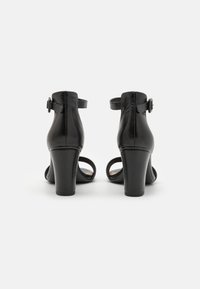 Black leather high heeled sandals with ankle straps, featuring a smooth texture and rounded open toe design, showing a wide block heel.