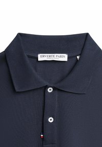 Polo bleu marine en tissu texturé, avec une patte de boutonnage à trois boutons et un col côtelé. L'étiquette indique « ERVERTE PARIS, FABRIQUÉ EN FRANCE ».