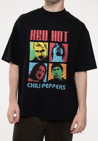 Black cotton t-shirt featuring a colorful graphic print with four stylized faces and the text "RED HOT CHILI PEPPERS" in blue.