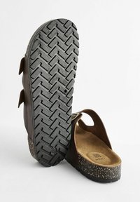 Braune Sandalen mit einer strukturierten schwarzen Sohle, ausgestattet mit zwei verstellbaren Riemen und einer gepolsterten Innensohle mit einem gesprenkelten Zwischensohlen-Design.