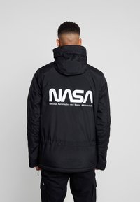 Zwarte hoodie-jack met een groot wit NASA-logo op de rug, met een gladde textuur en een verstelbaar trekkoord in de taille.