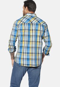 Plaid shirt in blue, yellow, and white; cotton material; long sleeves rolled at cuffs; curved hem; back yoke detail visible.
