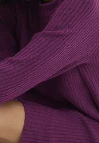 Maglione a coste viola con collo alto e maniche lunghe, caratterizzato da una texture morbida e un design aderente.