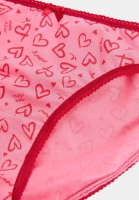 Rosa Baumwollunterwäsche mit einem Herzmuster in Rot, verziert mit einem roten Spitzenrand und einem kleinen Schleifchen am Taillenbund.