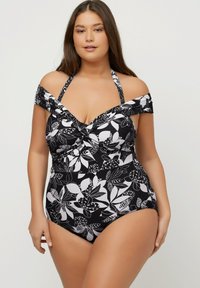 Maillot de bain à imprimé floral noir et blanc avec design décolleté, détail torsadé au niveau de la poitrine et coupe bikini. Fabriqué en tissu extensible pour plus de confort.
