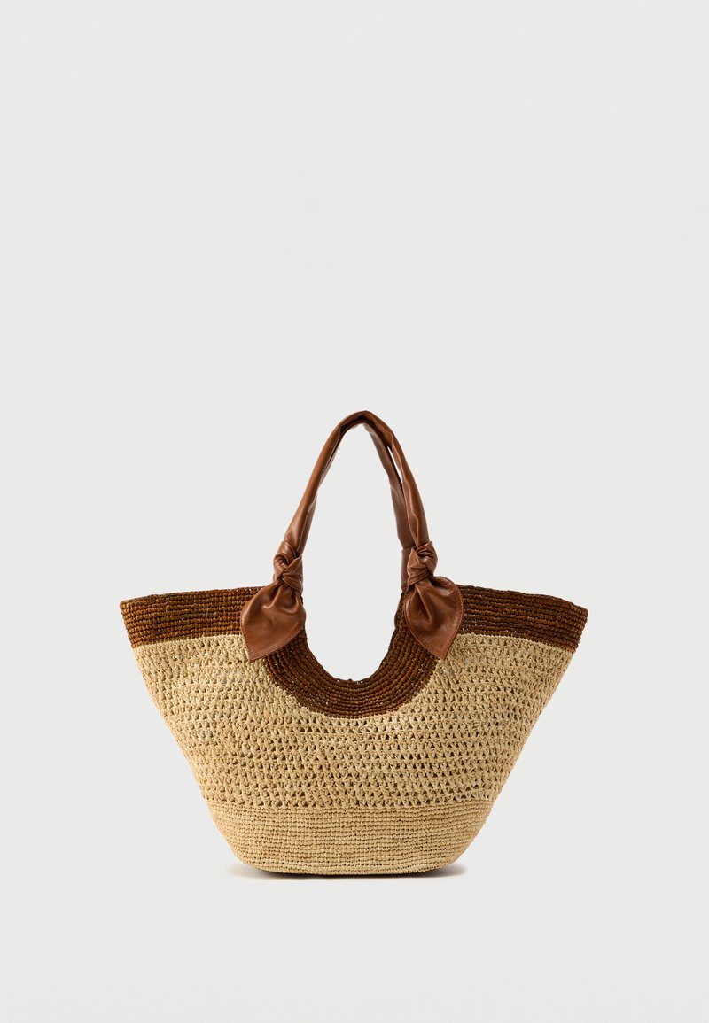 Τσάντα ώμου από πλεκτό άχυρο με βάση σε φυσικό χρ ώμα, σκουρόχρωμες καφέ λεπτομέρειες και καφέ δερμάτινες λαβές με κόμπους στις άκρες.