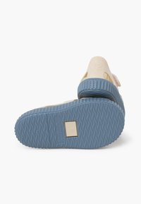 Beige clog with a textured blue outsole. Features a ventilation design and raised number 22 embossed on the back. Smooth upper material.