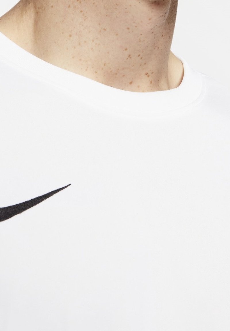 Cou et haut de la poitrine d'une personne portant une chemise blanche avec un logo Nike swoosh noir sur le côté gauche.