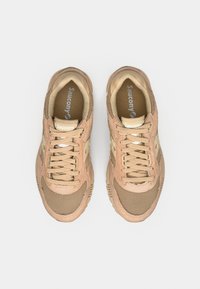 Bež tenisice od mrežastog materijala s antilop detaljima, s vezicama, podstavljenim okovratnikom i jastučićastim potplatom. Logotip vidljiv na jeziku tenisice.