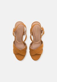 Brune semskede hælede sandaler med en krydset frontremdesign, ankelrem med spænde og flad sål. Brandnavn præget indvendig.