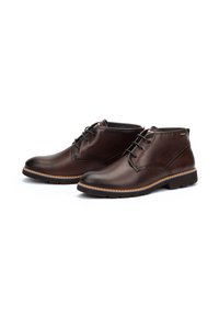Botas de cuero marrón hasta el tobillo con punta redonda, diseño de cordones, costuras en contraste y suela de goma. Textura suave y acentos mínimos.