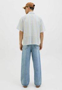 Korte mouwen shirt gemaakt van lichte, ademende stof met een gestreept patroon in blauw, geel en crème. Gecombineerd met wijde spijkerbroek.