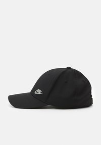 Sort baseball cap med en buet skygge, lavet af tekstureret stof, med et sølvfarvet Nike-logo på forsiden og ventilationshuller på siderne.