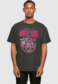 Juodas didelis t-shirt, pagamintas iš medvilnės, su išblukusiu grupės Mötley Crüe grafiniu spaudiniu ir rožiniu pentagramu.