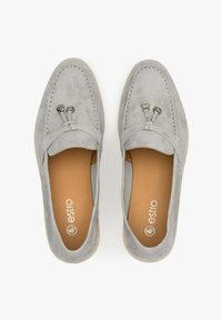 Light gray suede loafers with a smooth texture, featuring decorative laces and metal accents. Interior has a tan color with a logo.