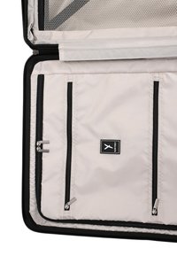 Lichtgrijze kofferinterieur met meerdere met rits afgesloten compartimenten en zwarte afwerking, met een Surifrey merklabel.