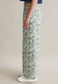 Floral maxi skirt in light fabric, featuring green and blue flowers on a cream background, with an elastic waistband and side pockets.